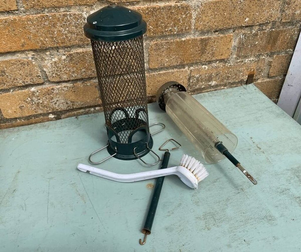 cleaning a bird feeder with brush and water